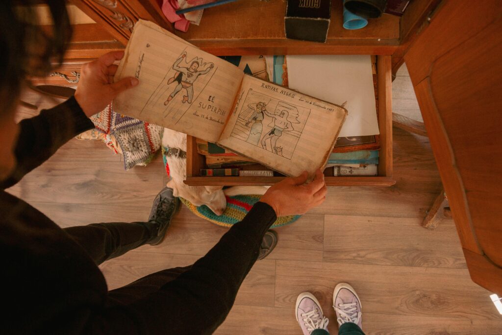 Vintage sketches found inside a wooden drawer being explored by two people indoors.